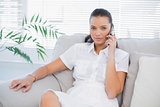 Serious woman in white dress having a phone call