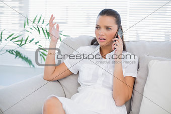 Worried woman in white dress having a phone call