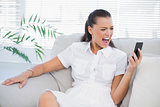 Irritated woman in white dress screaming at her smartphone