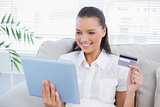 Cheerful cute woman buying online using her tablet pc