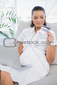 Pensive pretty woman buying online using laptop
