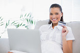 Cheerful gorgeous woman buying online using laptop