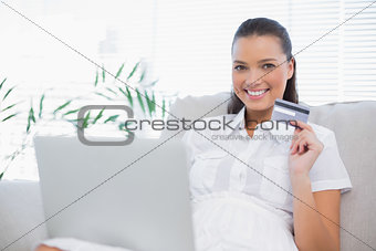 Cheerful gorgeous woman buying online using laptop