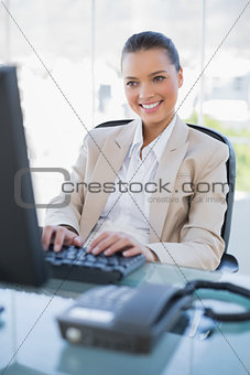Smiling gorgeous businesswoman working on computer