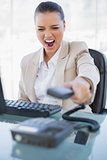 Angry businesswoman screaming while hanging up the phone