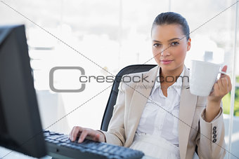 Relaxed businesswoman holding coffee looking at camera