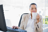 Smiling sophisticated businesswoman smelling coffee