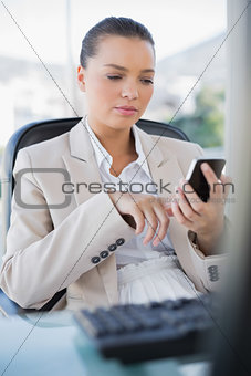 Focused sophisticated businesswoman text messaging