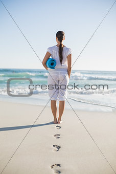 Rear view of gorgeous woman holding exercise mat