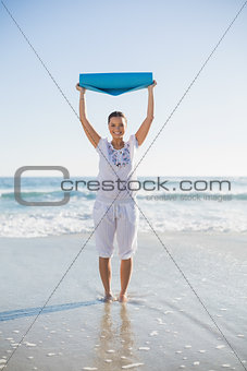 Happy woman holding exercise mat over her head