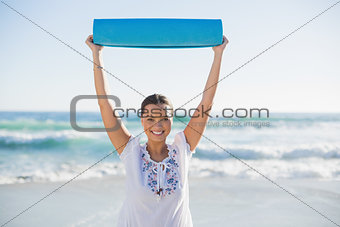 Smiling woman holding exercise mat over her head