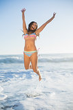 Laughing woman in bikini jumping in the sea