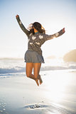Stylish woman jumping on the beach