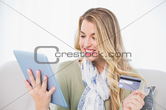 Cheerful pretty blonde using her credit card to buy online