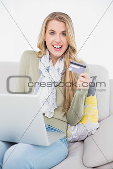 Cheerful cute blonde using her credit card to buy online