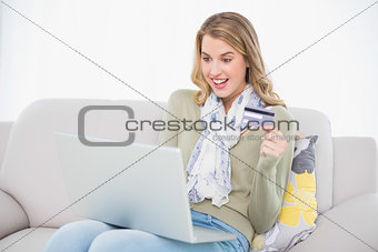 Surprised cute blonde using her credit card to buy online