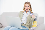Smiling cute blonde using her credit card to buy online