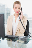 Frowning pretty businesswoman answering the phone