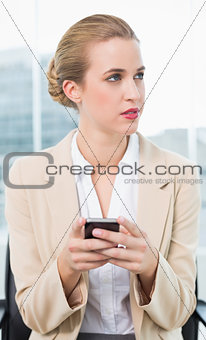 Pensive attractive businesswoman text messaging