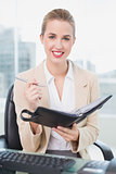 Smiling attractive businesswoman writing on her agenda