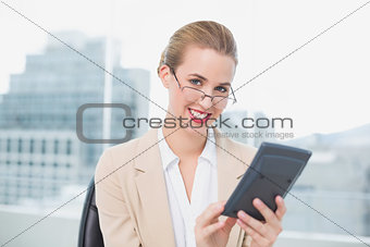 Smiling businesswoman with glasses using calculator