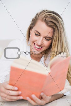 Gorgeous model lying on cosy bed reading book