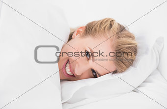 Smiling pretty model relaxing in cosy bed