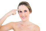Smiling woman pointing at her forehead posing
