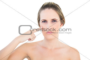 Serious blonde woman pointing at her cheek