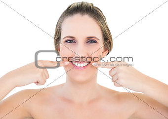 Smiling woman pointing at wrinkle on her mouth corners