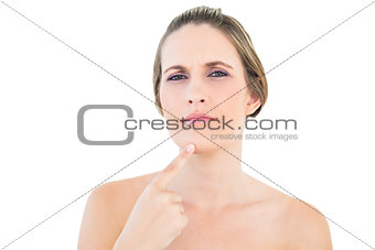 Thoughtful woman pointing at her chin looking at camera