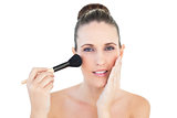 Relaxed woman using blusher brush