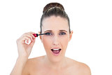 Shocked young woman applying mascara