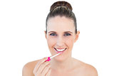 Smiling attractive woman applying lip gloss