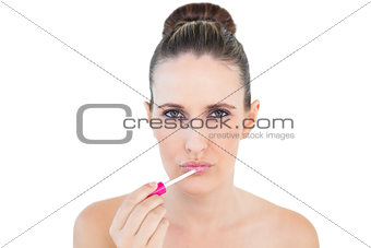 Serious beautiful woman applying lip gloss