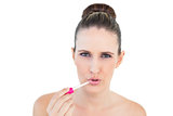 Sensual young woman applying lip gloss