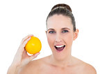 Surprised gorgeous woman holding orange