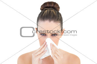 Woman looking upset at camera blowing nose
