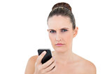 Pretty woman holding phone looking angry at camera