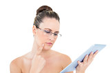 Thoughtful woman wearing glasses using tablet