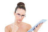Pensive woman wearing glasses using tablet