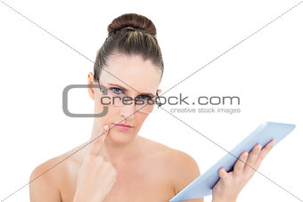 Pensive woman wearing glasses using tablet