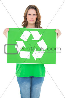 Unsmiling environmental activist holding recycling sign
