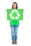 Environmental activist holding recycling sign looking at camera