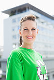 Smiling woman wearing green shirt with recycling symbol on it