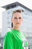 Unsmiling woman wearing green shirt with recycling symbol