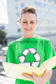 Woman wearing tshirt with recycling symbol holding notebook