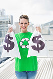 Smiling woman in green recyling tshirt showing money bags