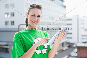 Cheerful woman wearing recycling tshirt using tablet