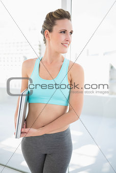 Smiling woman in sportswear holding laptop